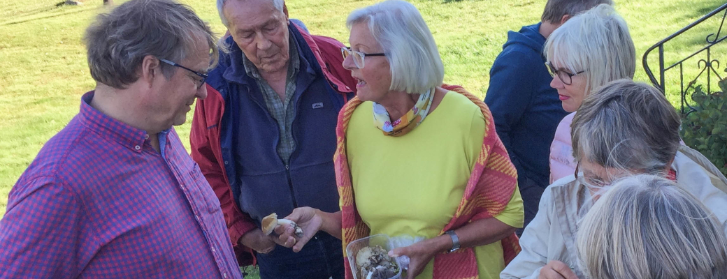 Syv person står å diskuterer soppene som en kvinne holder i hånden.